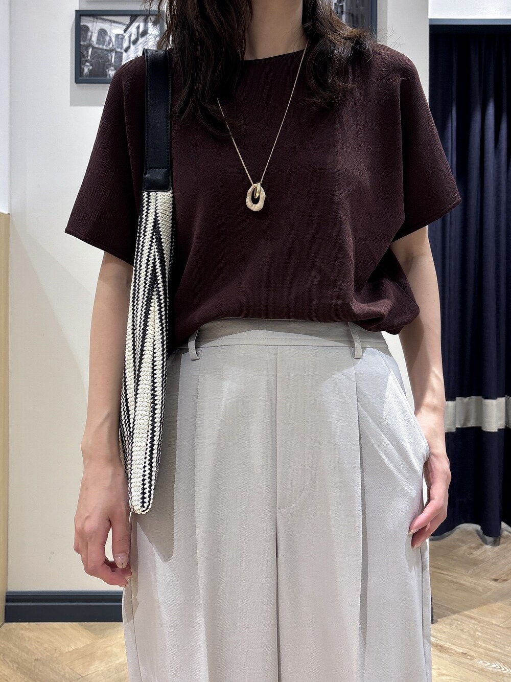 ブラウン系のニット/セーター、ベージュ系のその他パンツ、ブラック系のショルダーバッグを着用したレディースの夏コーディネートの4枚目の写真