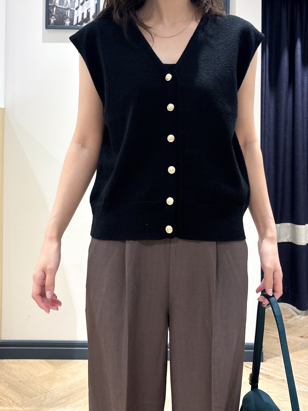 ブラック系のニット/セーター、ブラウン系のその他パンツ、グリーン系のショルダーバッグを着用したレディースの夏コーディネートの4枚目の写真