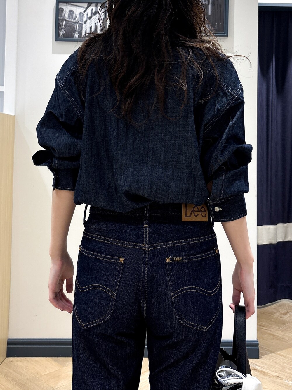 ブルー系のシャツ/ブラウス、ブルー系のデニムパンツ、ブラック系のショルダーバッグを着用したレディースの秋コーディネートの6枚目の写真