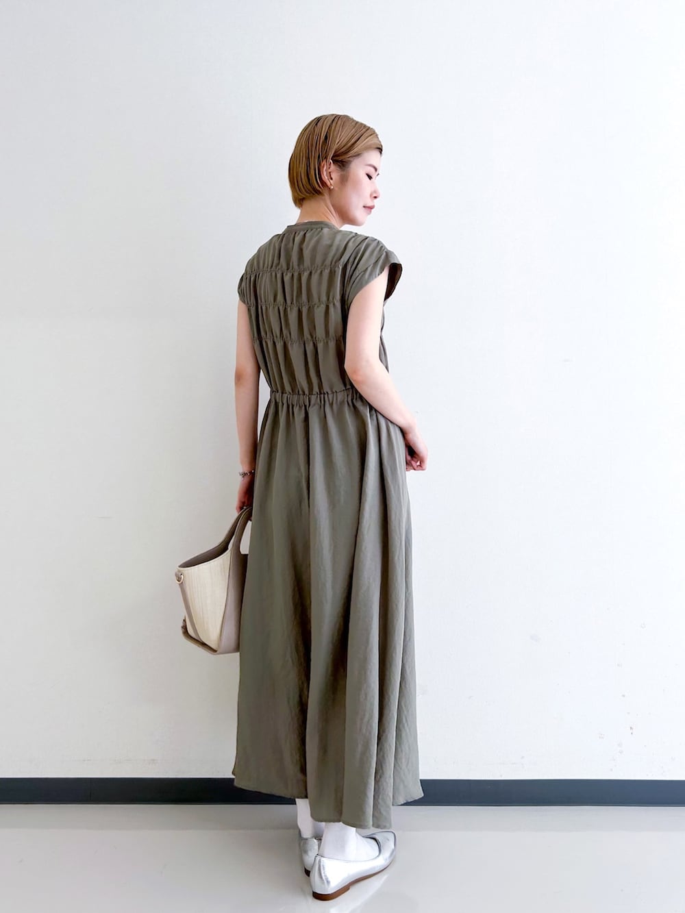 グリーン系のワンピース、グレー系のトートバッグ、シルバー系のその他シューズを着用したレディースの春コーディネートの3枚目の写真