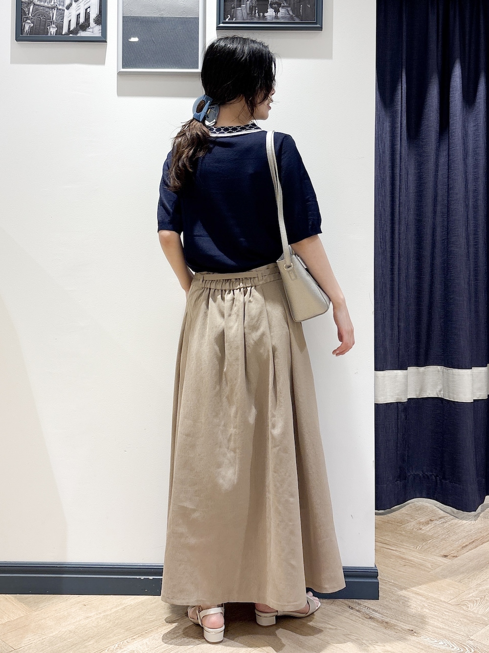 ブルー系のニット/セーター、ベージュ系のスカート、シルバー系のショルダーバッグを着用したレディースの夏コーディネートの3枚目の写真
