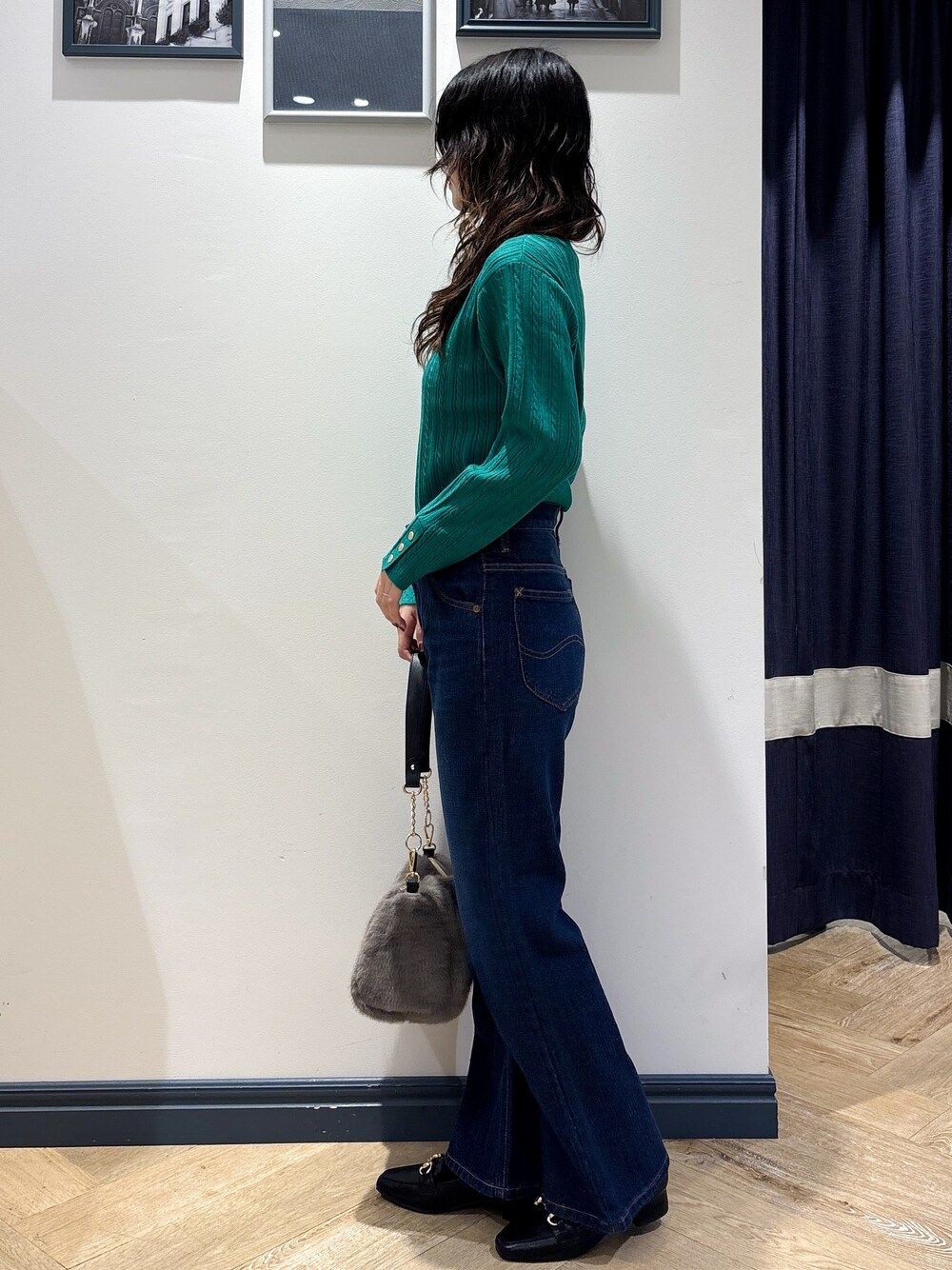 グリーン系のニット/セーター、ブルー系のデニムパンツ、グレー系のショルダーバッグを着用したレディースの秋コーディネートの2枚目の写真