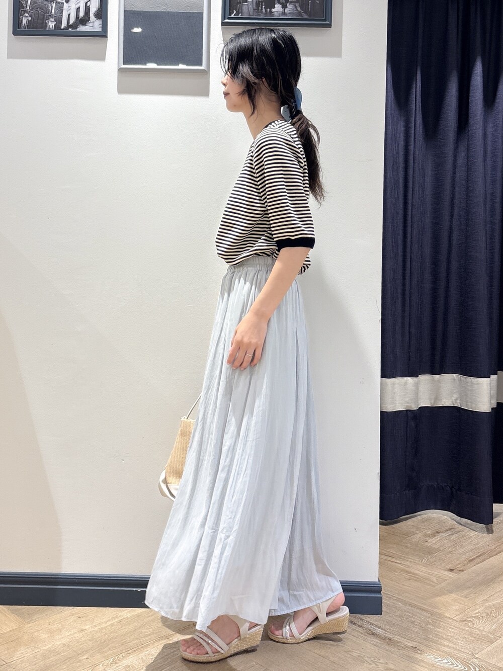 ブラック系のニット/セーター、ブルー系のその他パンツ、ホワイト系のショルダーバッグを着用したレディースの夏コーディネートの2枚目の写真