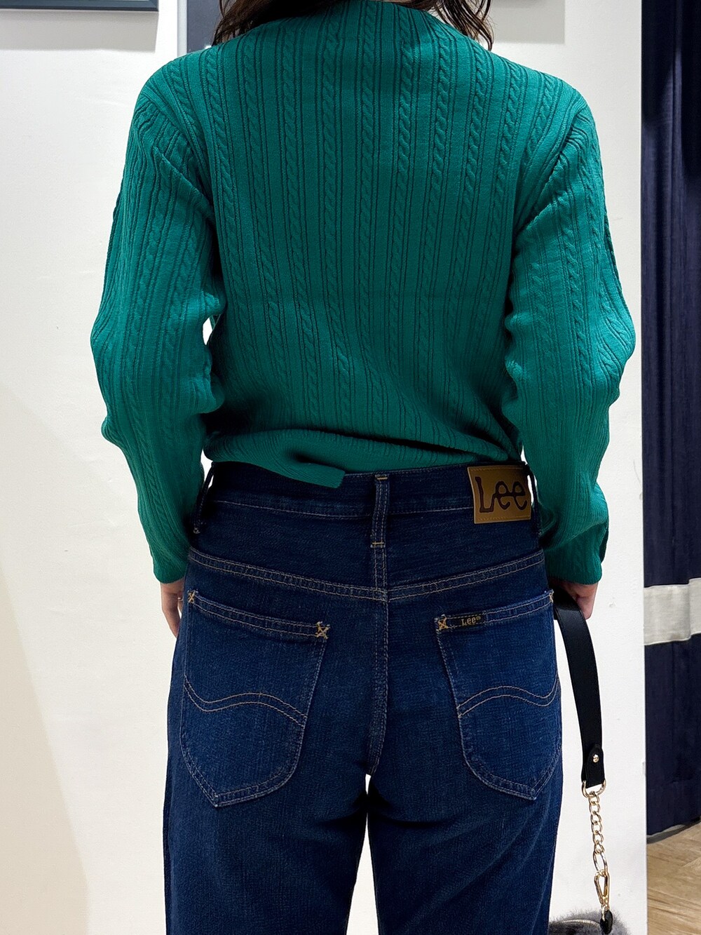 グリーン系のニット/セーター、ブルー系のデニムパンツ、グレー系のショルダーバッグを着用したレディースの秋コーディネートの6枚目の写真