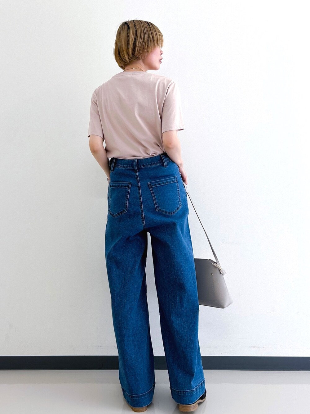 ピンク系のTシャツ/カットソー、ブルー系のデニムパンツ、グレー系のショルダーバッグを着用したレディースの春コーディネートの3枚目の写真