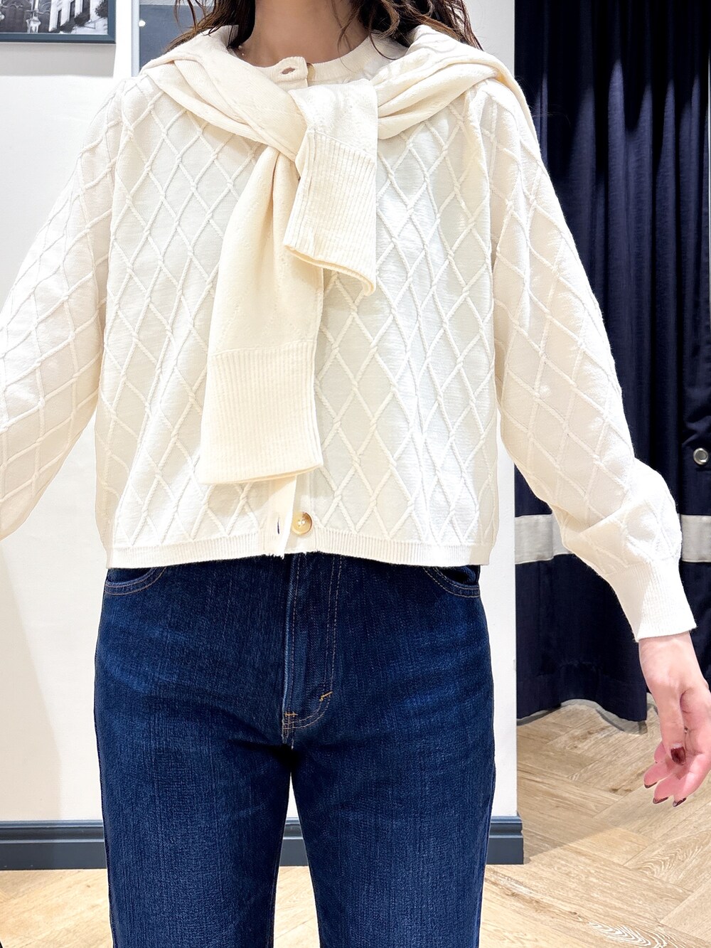 ホワイト系のカーディガン/ボレロ、ホワイト系のニット/セーター、ブルー系のデニムパンツを着用したレディースの秋コーディネートの4枚目の写真