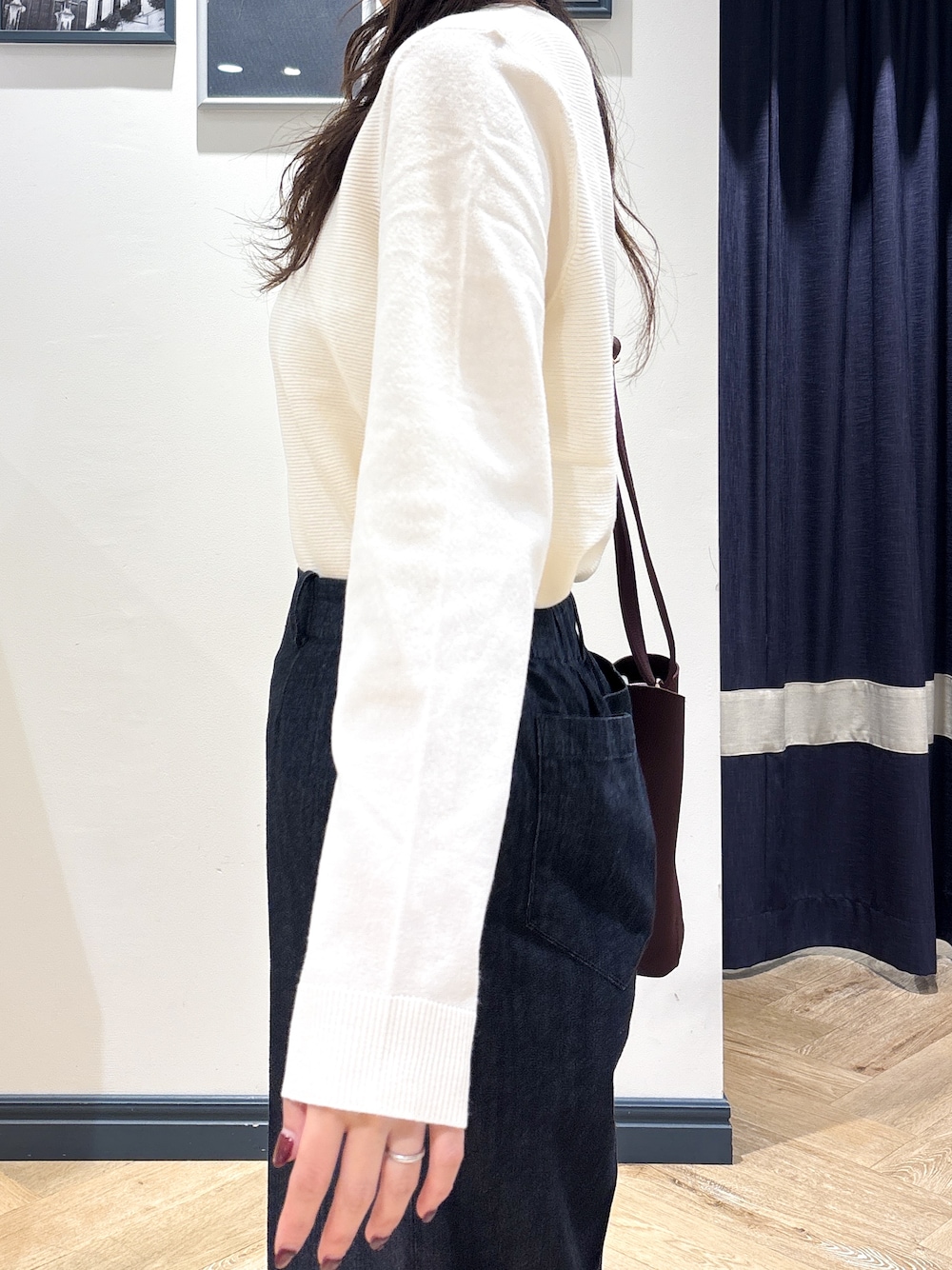 ホワイト系のニット/セーター、ブラック系のデニムパンツ、レッド系のショルダーバッグを着用したレディースの秋コーディネートの5枚目の写真