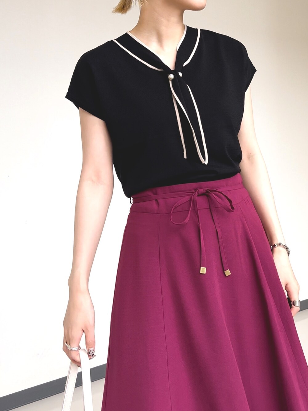 ブラック系のニット/セーター、ピンク系のスカート、ブラック系のサンダルを着用したレディースの夏コーディネートの2枚目の写真