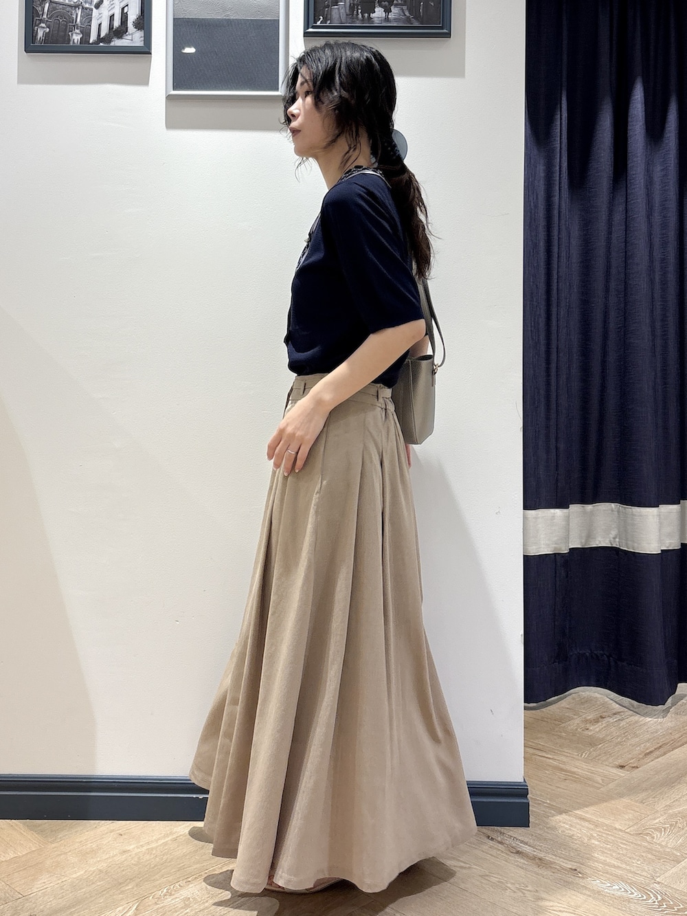 ブルー系のニット/セーター、ベージュ系のスカート、シルバー系のショルダーバッグを着用したレディースの夏コーディネートの2枚目の写真