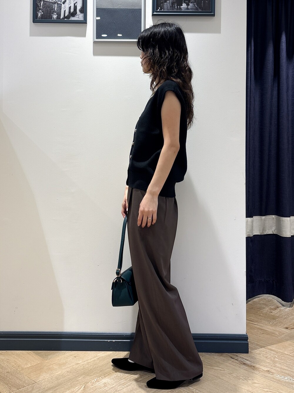 ブラック系のニット/セーター、ブラウン系のその他パンツ、グリーン系のショルダーバッグを着用したレディースの夏コーディネートの2枚目の写真