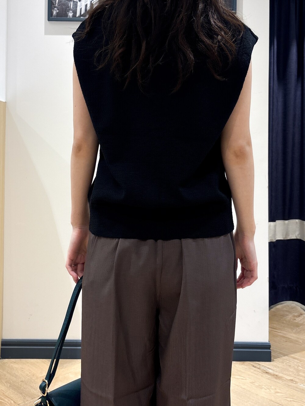 ブラック系のニット/セーター、ブラウン系のその他パンツ、グリーン系のショルダーバッグを着用したレディースの夏コーディネートの6枚目の写真