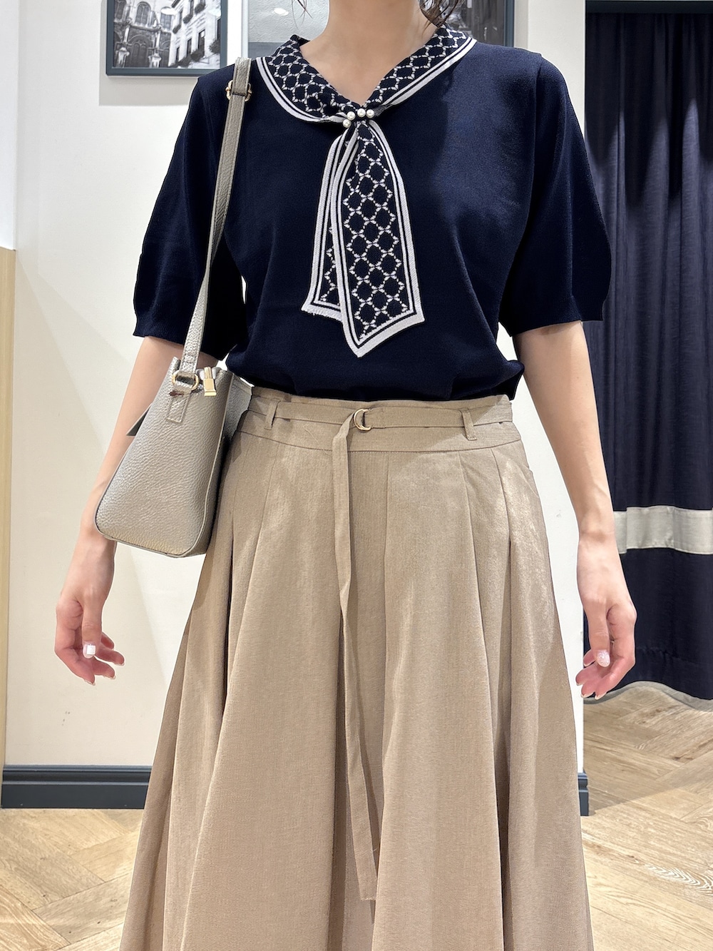 ブルー系のニット/セーター、ベージュ系のスカート、シルバー系のショルダーバッグを着用したレディースの夏コーディネートの4枚目の写真