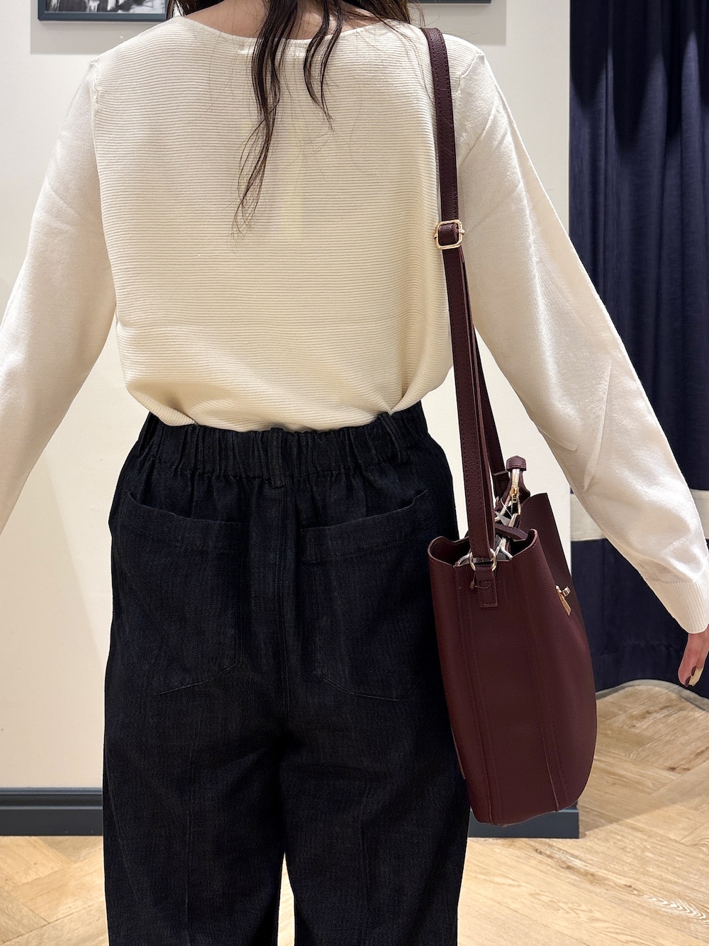 ホワイト系のニット/セーター、ブラック系のデニムパンツ、レッド系のショルダーバッグを着用したレディースの秋コーディネートの4枚目の写真