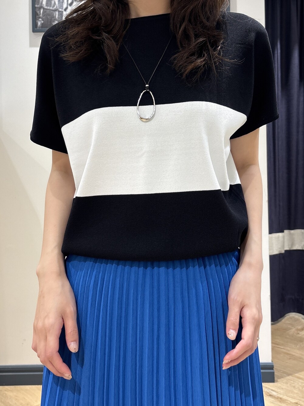 ブラック系のニット/セーター、ブルー系のスカート、シルバー系のネックレスを着用したレディースの夏コーディネートの4枚目の写真