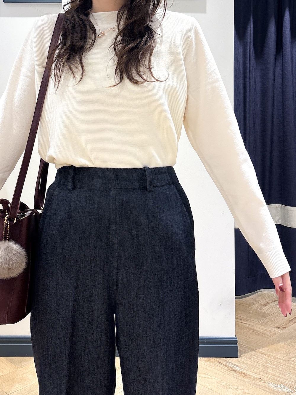 ホワイト系のニット/セーター、ブラック系のデニムパンツ、レッド系のショルダーバッグを着用したレディースの秋コーディネートの6枚目の写真