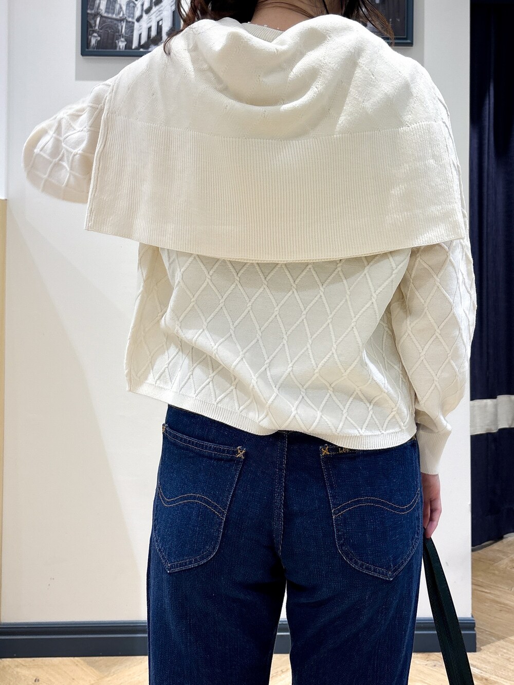 ホワイト系のカーディガン/ボレロ、ホワイト系のニット/セーター、ブルー系のデニムパンツを着用したレディースの秋コーディネートの6枚目の写真