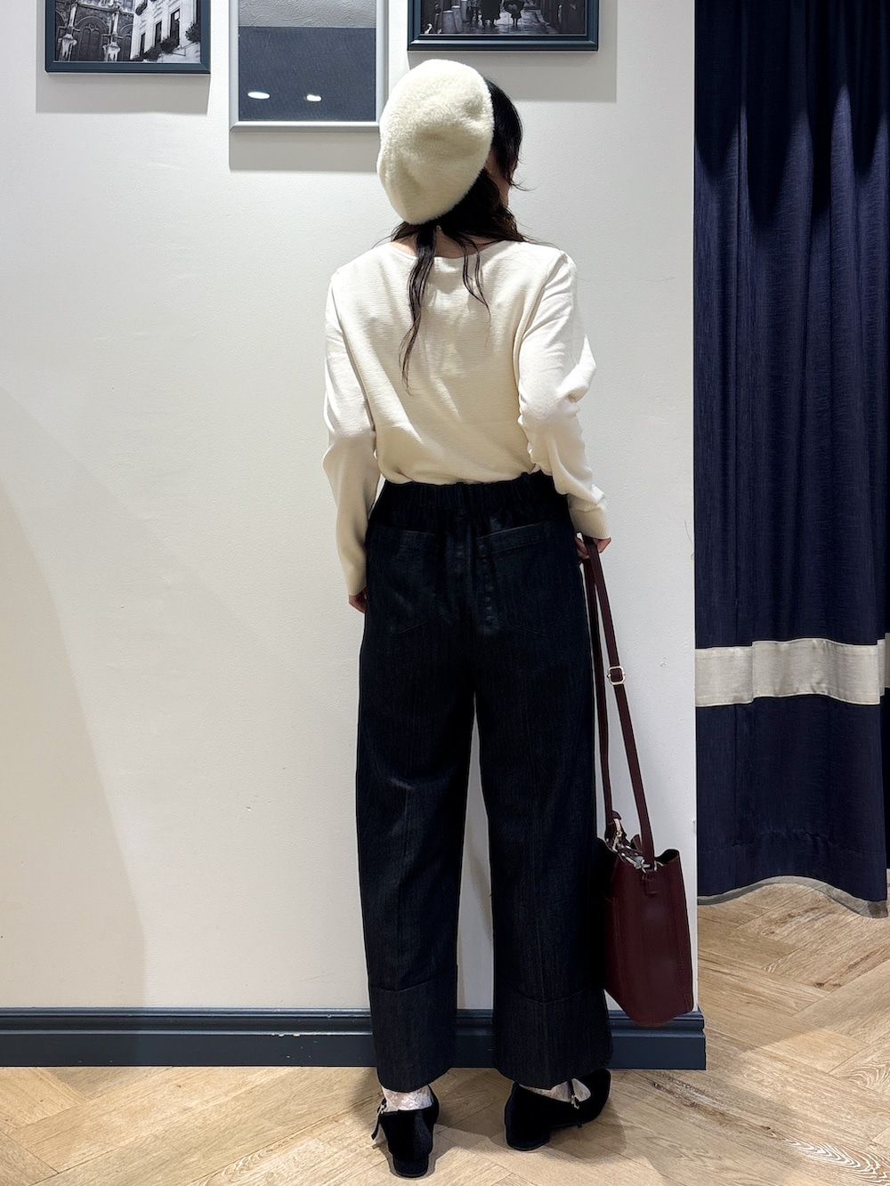 ホワイト系のニット/セーター、ブラック系のデニムパンツ、レッド系のショルダーバッグを着用したレディースの秋コーディネートの3枚目の写真
