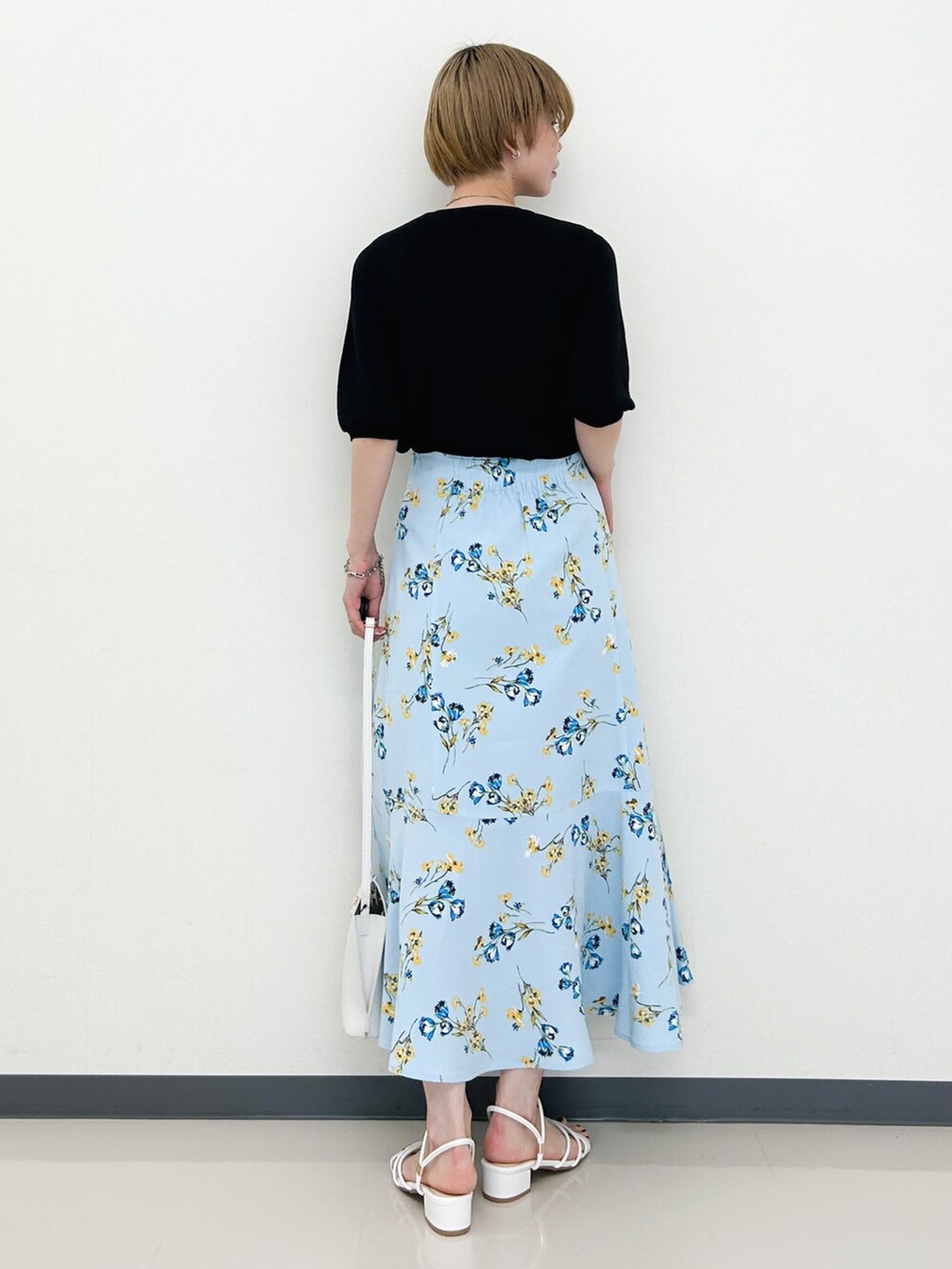 ブラック系のニット/セーター、ブルー系のスカート、ホワイト系のショルダーバッグを着用したレディースの春コーディネートの3枚目の写真