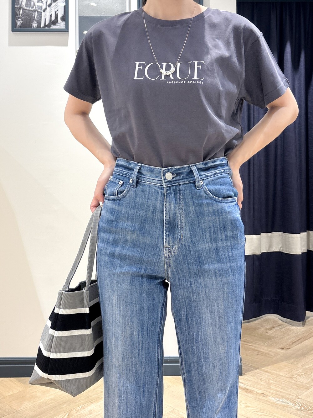 グレー系のTシャツ/カットソー、ブルー系のデニムパンツ、グレー系のトートバッグを着用したレディースの夏コーディネートの4枚目の写真