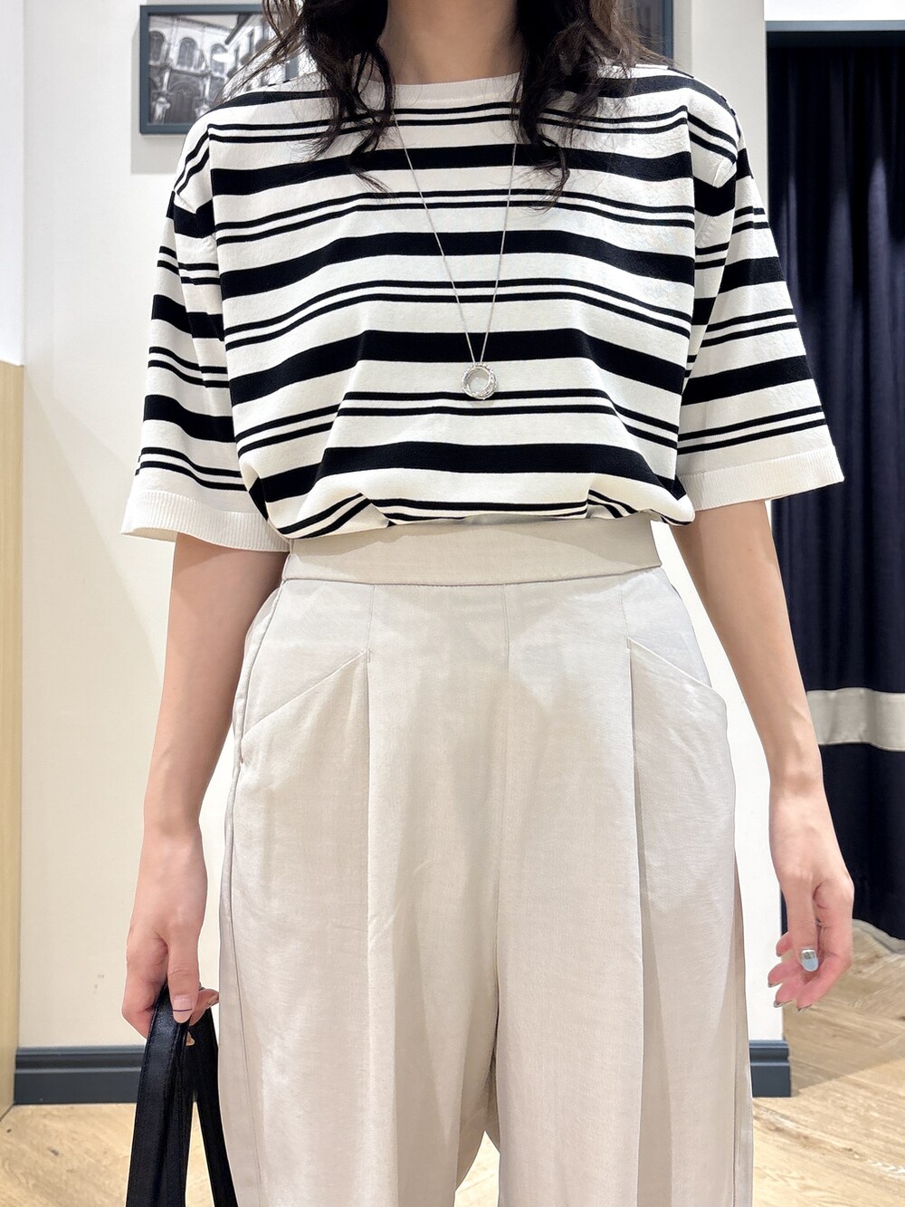 ホワイト系のニット/セーター、ベージュ系のその他パンツ、ブラック系のトートバッグを着用したレディースの夏コーディネートの4枚目の写真