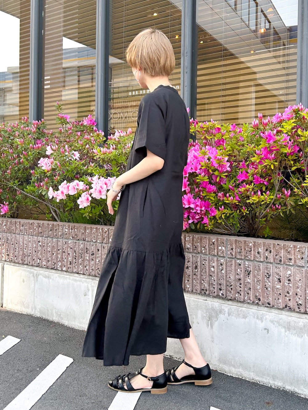 ブラック系のワンピース、ホワイト系のトートバッグ、ブラック系のサンダルを着用したレディースの春コーディネートの2枚目の写真