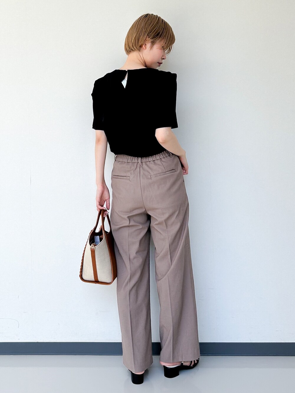 ブラック系のセットアップ、ブラウン系のその他パンツ、イエロー系のトートバッグを着用したレディースの春コーディネートの3枚目の写真