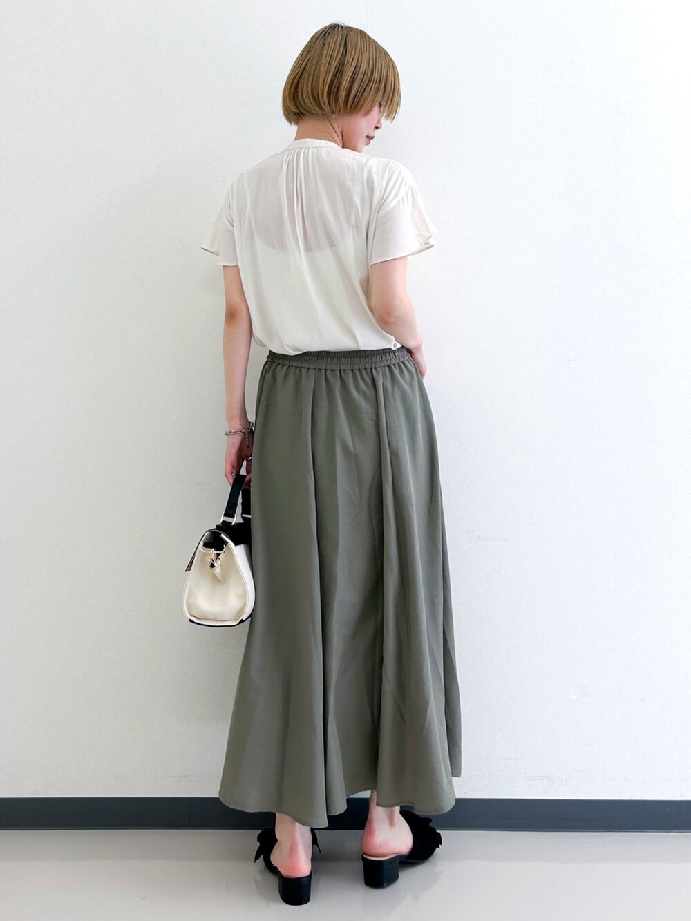 ホワイト系のシャツ/ブラウス、グリーン系のスカート、ブラック系のショルダーバッグを着用したレディースの春コーディネートの3枚目の写真