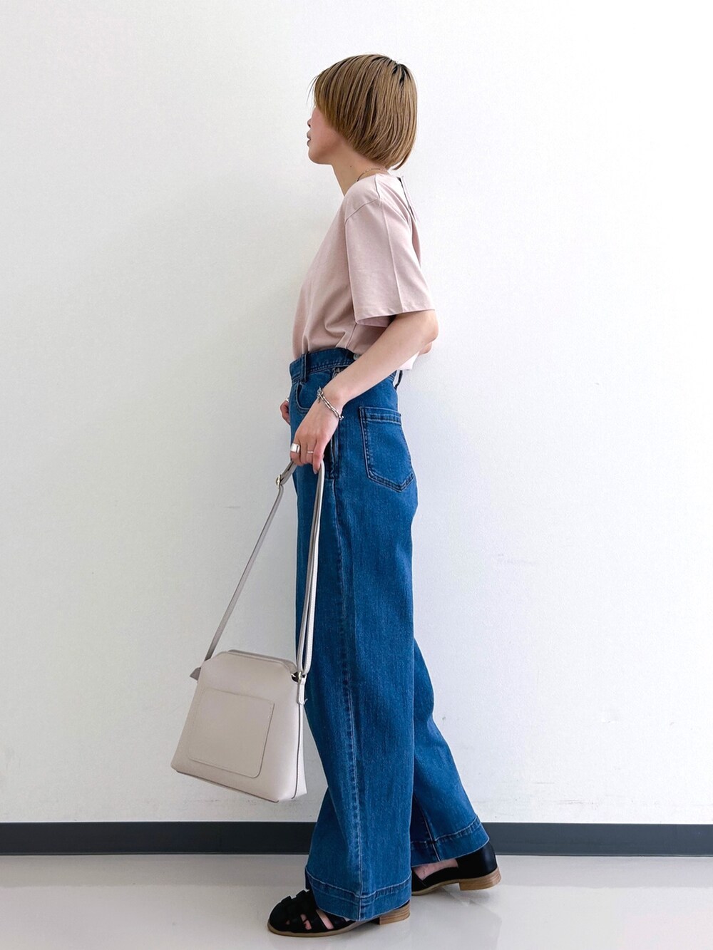 ピンク系のTシャツ/カットソー、ブルー系のデニムパンツ、グレー系のショルダーバッグを着用したレディースの春コーディネートの2枚目の写真