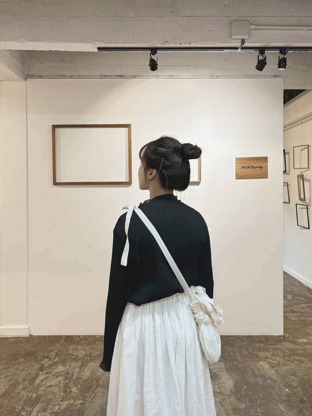 ホワイト系のスカート、ブラウン系のサンダル、ブラック系のスウェットを着用したレディースの秋コーディネートの4枚目の写真