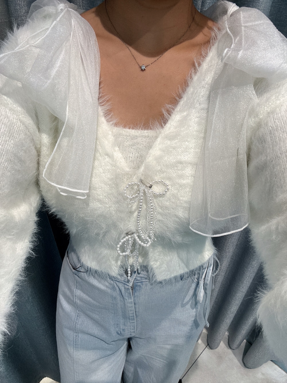 ホワイト系のカーディガン/ボレロ、ブルー系のデニムパンツ、グレー系のトートバッグを着用したレディースの秋コーディネートの3枚目の写真