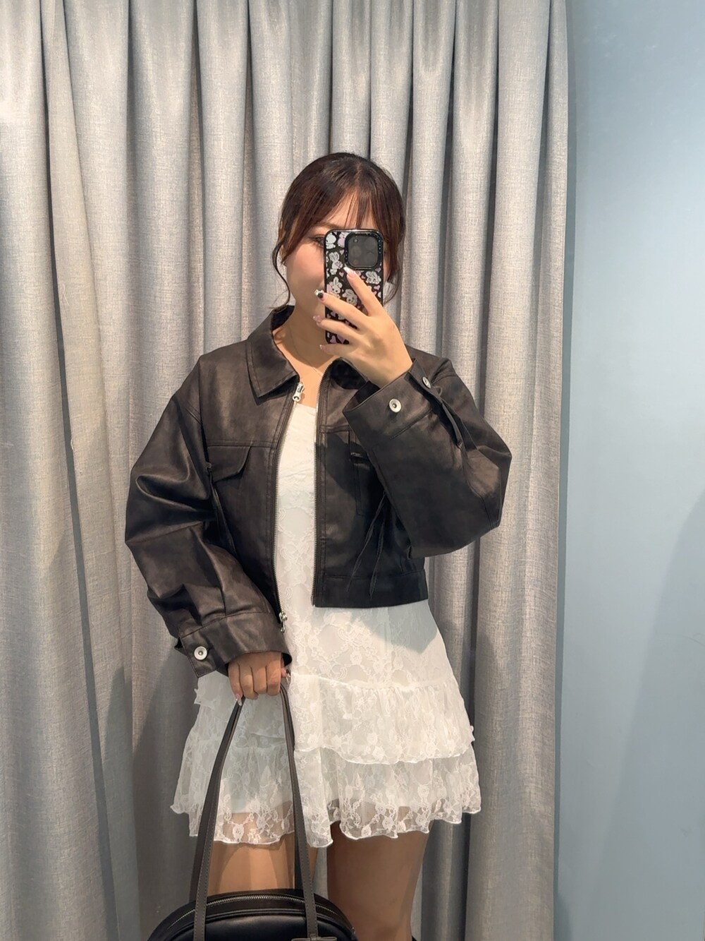 ブラック系のブルゾン、ホワイト系のワンピース、ブラック系のブーツを着用したレディースの秋コーディネートの2枚目の写真