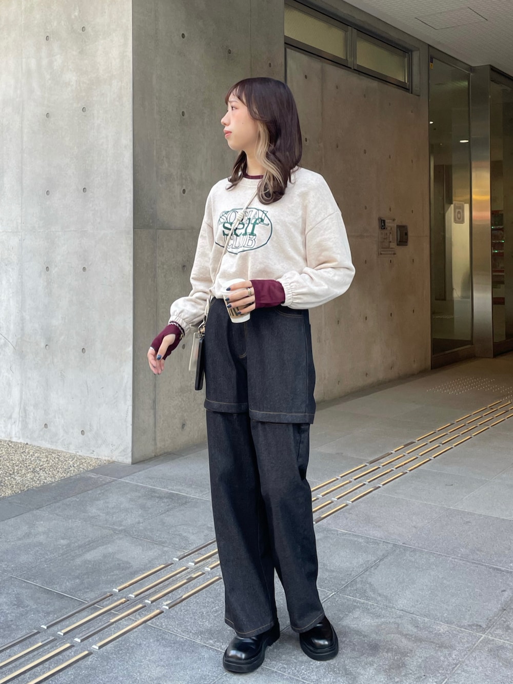 ブラック系のデニムパンツ、ブラック系のブーツ、ベージュ系のスウェットを着用したレディースの冬コーディネートの4枚目の写真