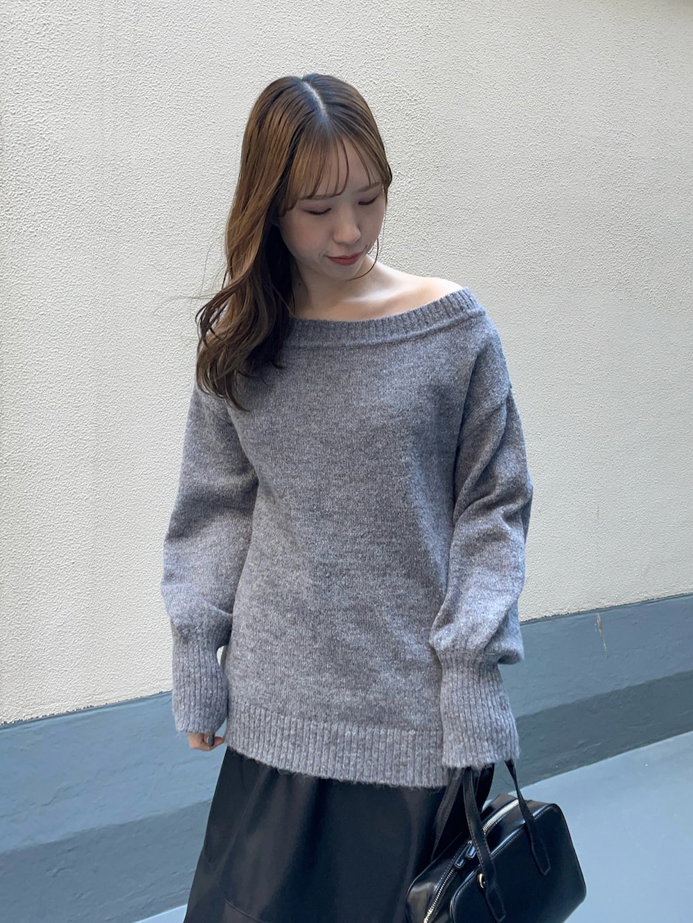 ブラック系のハンドバッグ、ブラック系のスカート、ブラック系のブーツを着用したレディースの冬コーディネートの4枚目の写真