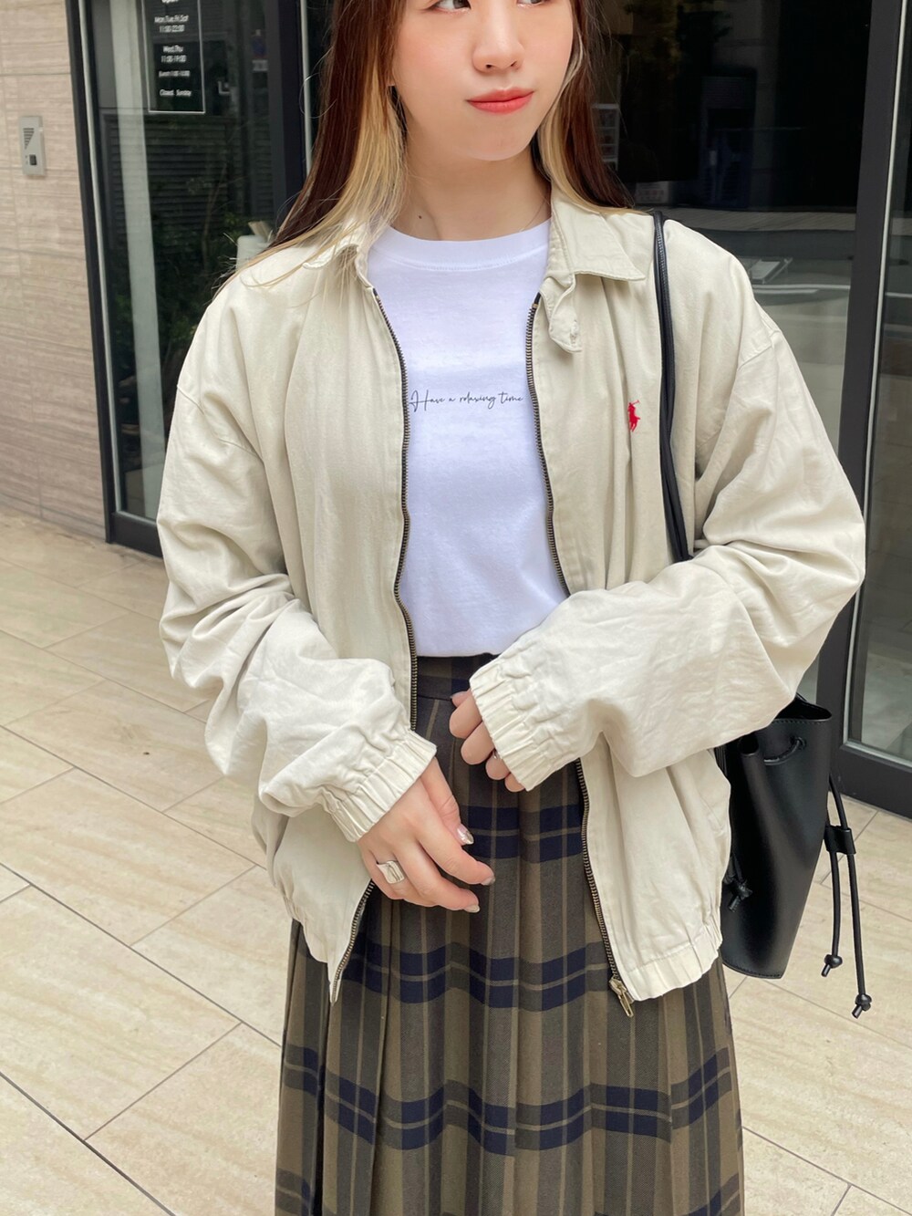 ブラック系のローファー、グリーン系のスカート、ベージュ系のジャケット/アウターを着用したレディースの春コーディネートの2枚目の写真