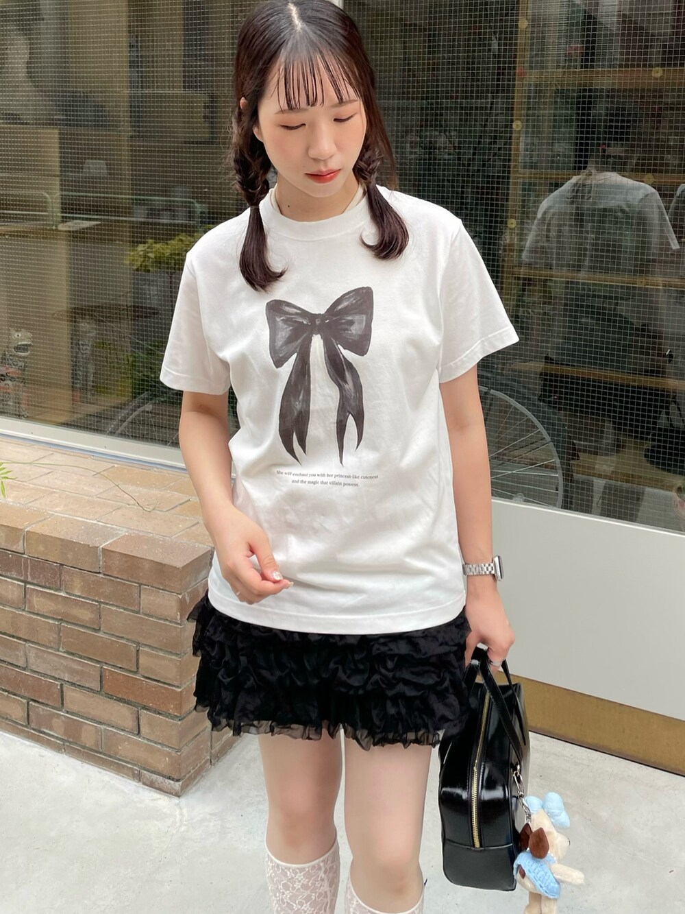 ホワイト系のTシャツ/カットソー、ブラック系のパンプス、ブラック系のハンドバッグを着用したレディースの夏コーディネートの4枚目の写真