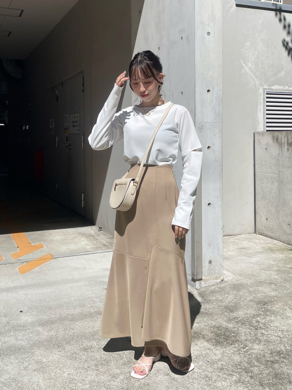 ベージュ系のスカート、ホワイト系のサンダル、ホワイト系のTシャツ/カットソーを着用したレディースの夏コーディネートの2枚目の写真