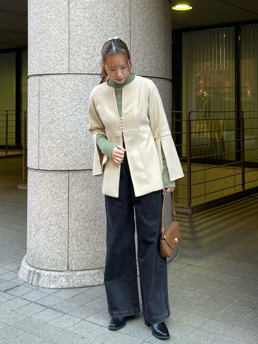 ホワイト系のノーカラーコート、グリーン系のニット/セーター、ブラック系のデニムパンツを着用したレディースの冬コーディネートの2枚目の写真