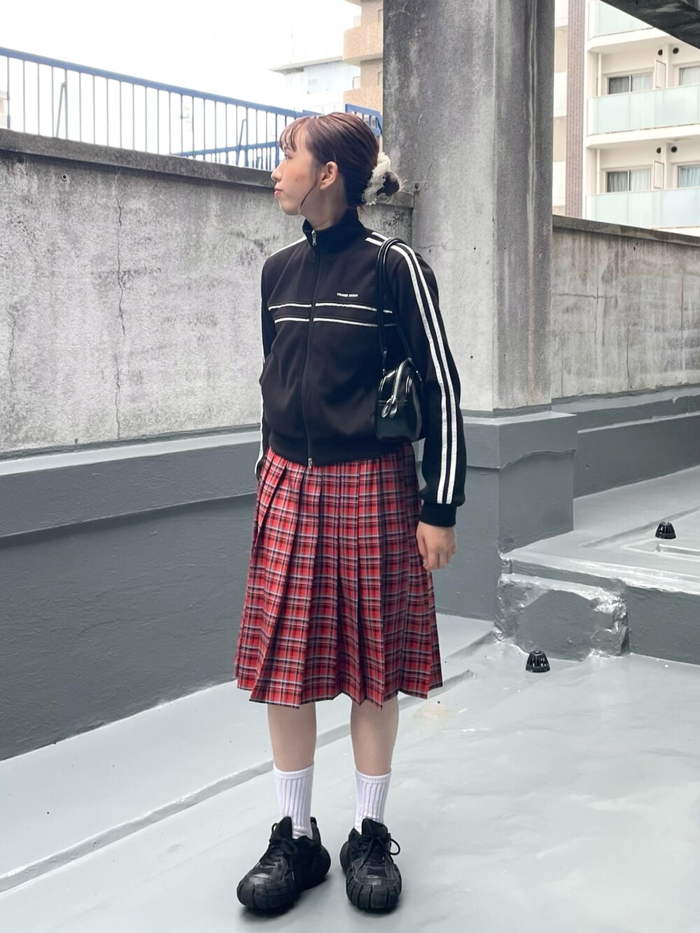 ブラック系のスニーカー、レッド系のスカート、ブラック系のショルダーバッグを着用したレディースの秋コーディネートの2枚目の写真