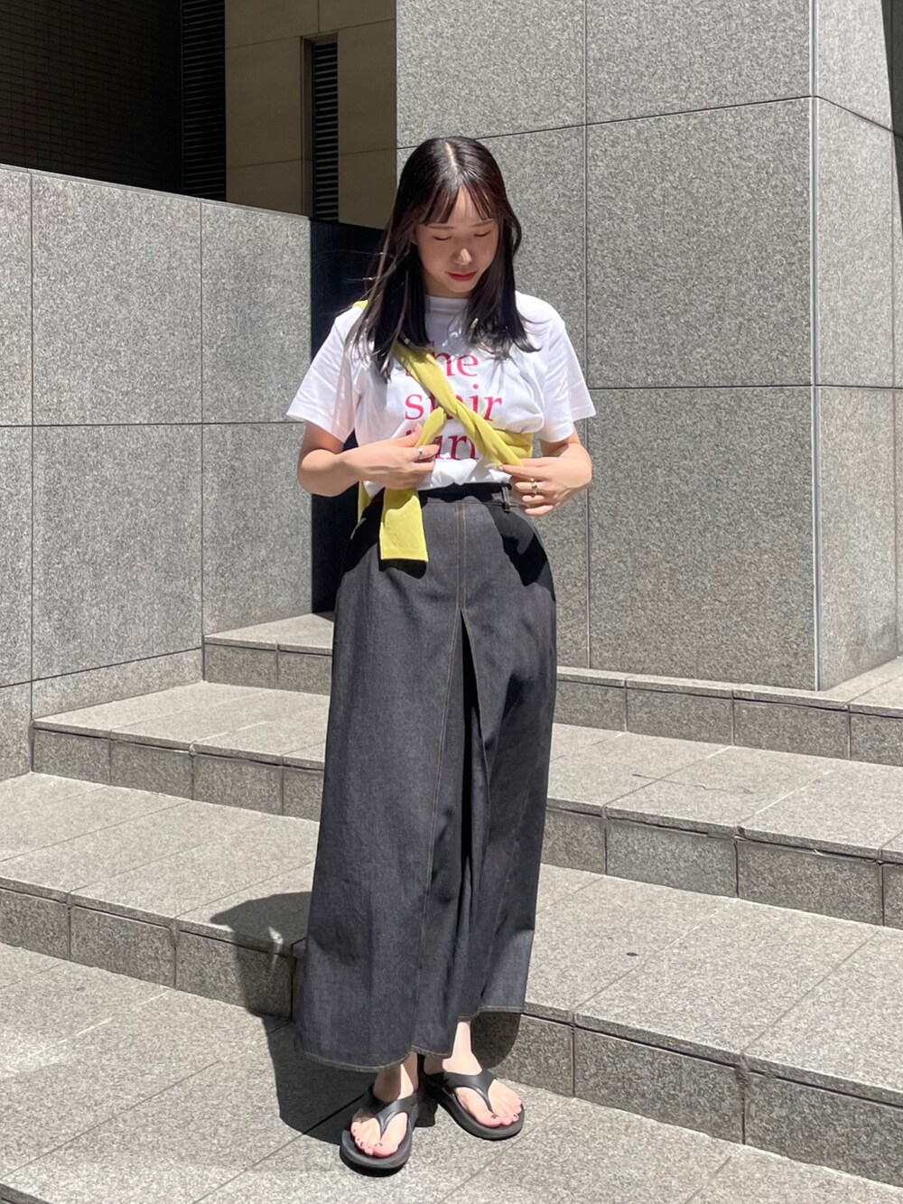 グリーン系のニット/セーター、ホワイト系のTシャツ/カットソー、ブラック系のスカートを着用したレディースの夏コーディネートの2枚目の写真