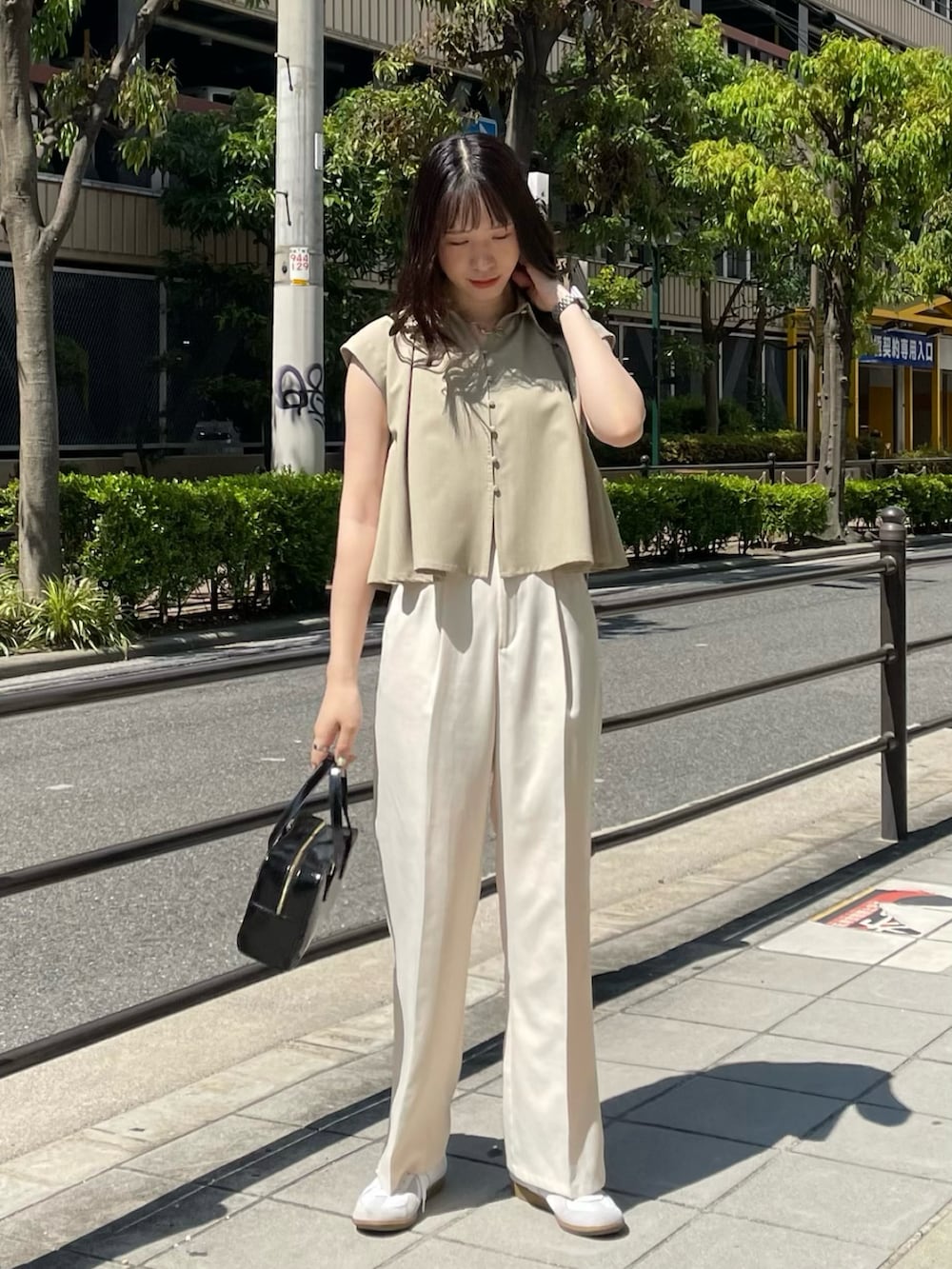 ホワイト系のスラックス、ホワイト系のスニーカー、ベージュ系のシャツ/ブラウスを着用したレディースの夏コーディネートの3枚目の写真