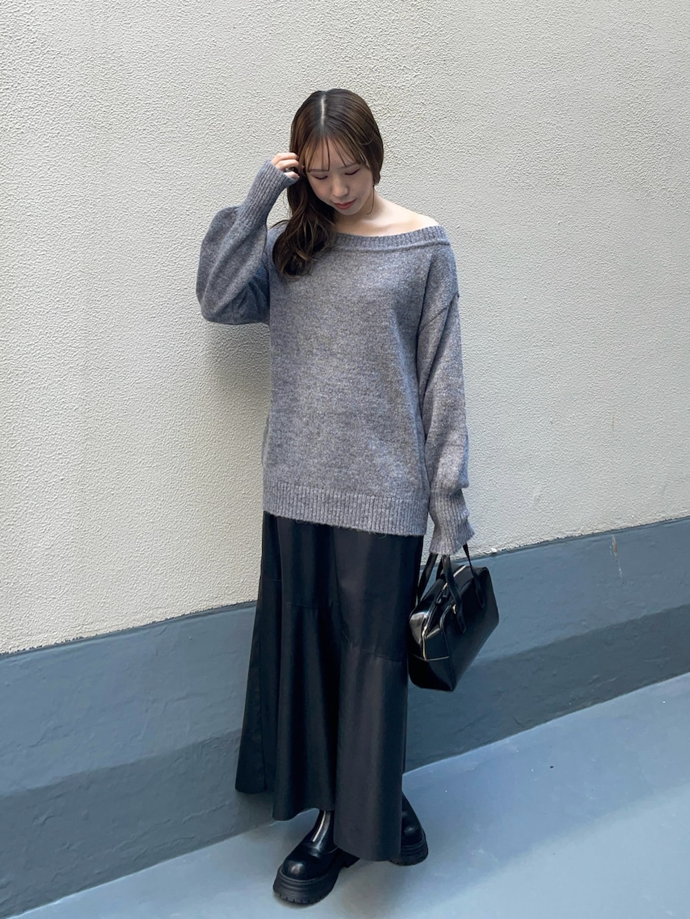 ブラック系のハンドバッグ、ブラック系のスカート、ブラック系のブーツを着用したレディースの冬コーディネートの3枚目の写真