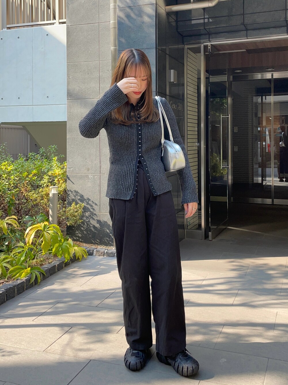 シルバー系のショルダーバッグ、グレー系のニット/セーター、ブラック系のスラックスを着用したレディースの冬コーディネートの2枚目の写真