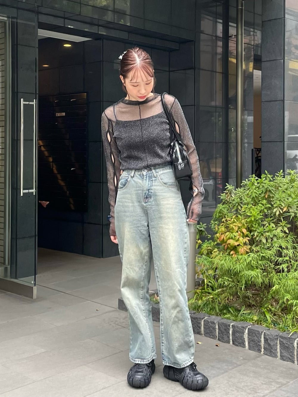 グリーン系のデニムパンツ、ブラック系のスニーカー、ブラック系のショルダーバッグを着用したレディースの秋コーディネートの2枚目の写真
