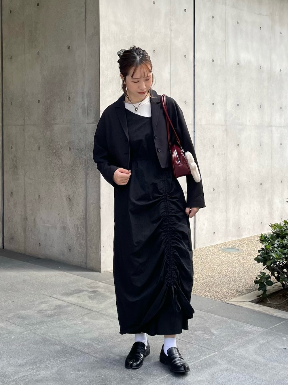 ブラック系のローファー、ブラック系のワンピース、レッド系のショルダーバッグを着用したレディースの秋コーディネートの2枚目の写真