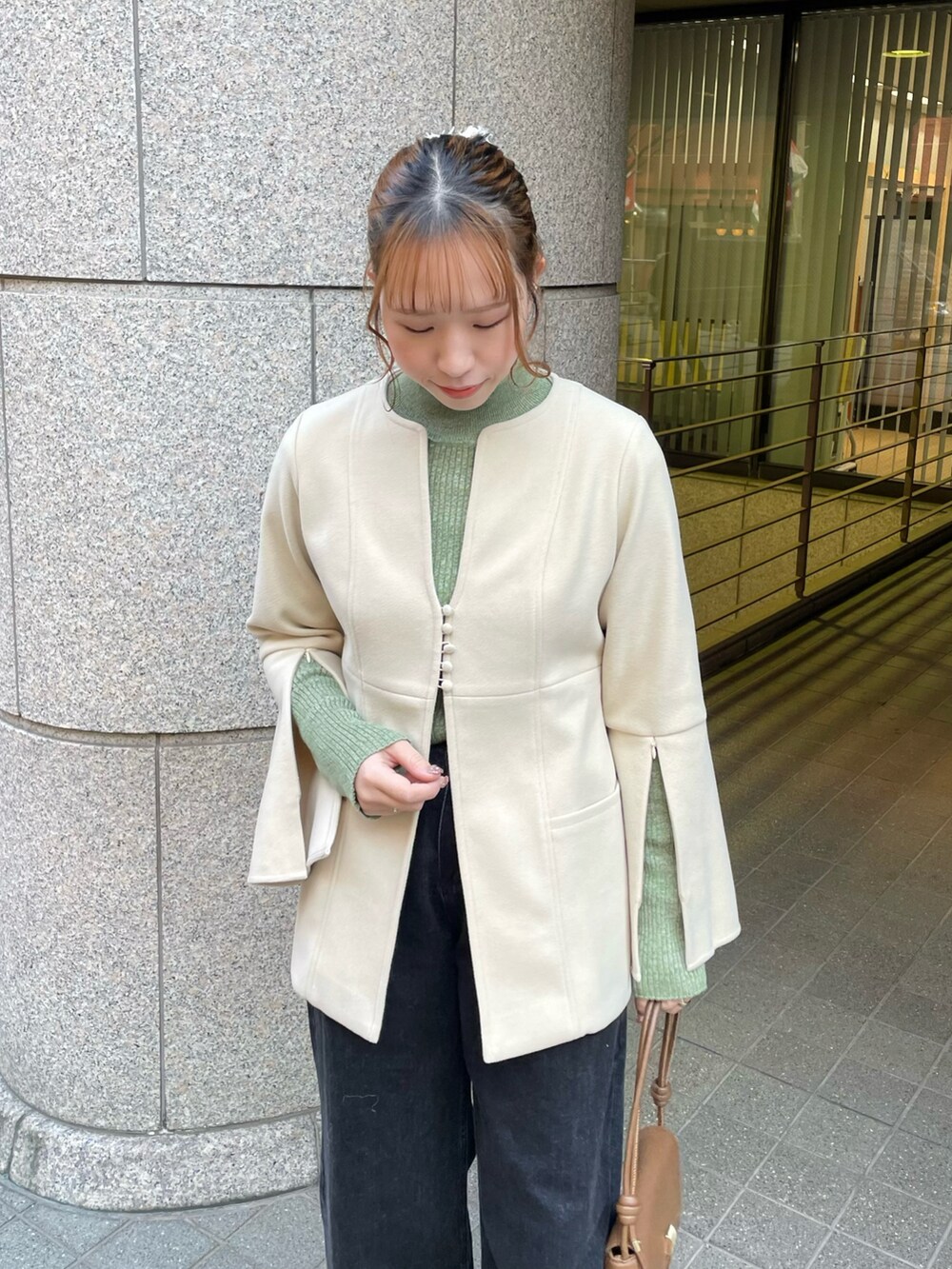 ホワイト系のノーカラーコート、グリーン系のニット/セーター、ブラック系のデニムパンツを着用したレディースの冬コーディネートの4枚目の写真