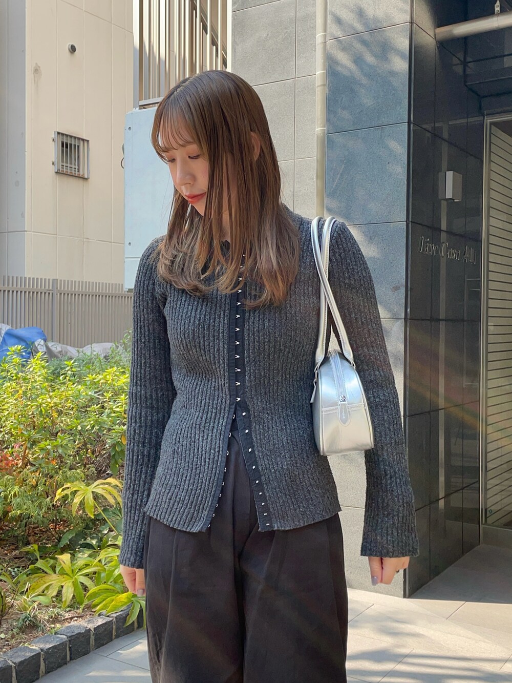 シルバー系のショルダーバッグ、グレー系のニット/セーター、ブラック系のスラックスを着用したレディースの冬コーディネートの3枚目の写真