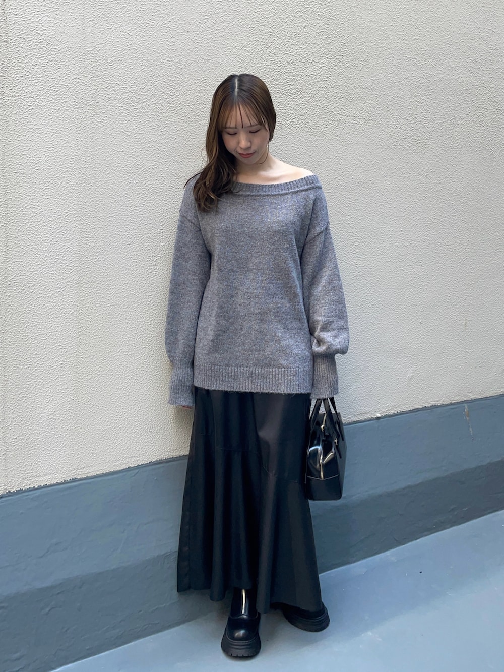 ブラック系のハンドバッグ、ブラック系のスカート、ブラック系のブーツを着用したレディースの冬コーディネートの2枚目の写真