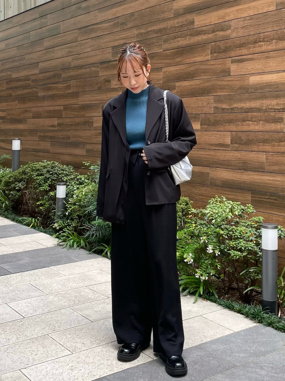 ブルー系のニット/セーター、シルバー系のショルダーバッグ、ブラック系のスラックスを着用したレディースの秋コーディネートの2枚目の写真