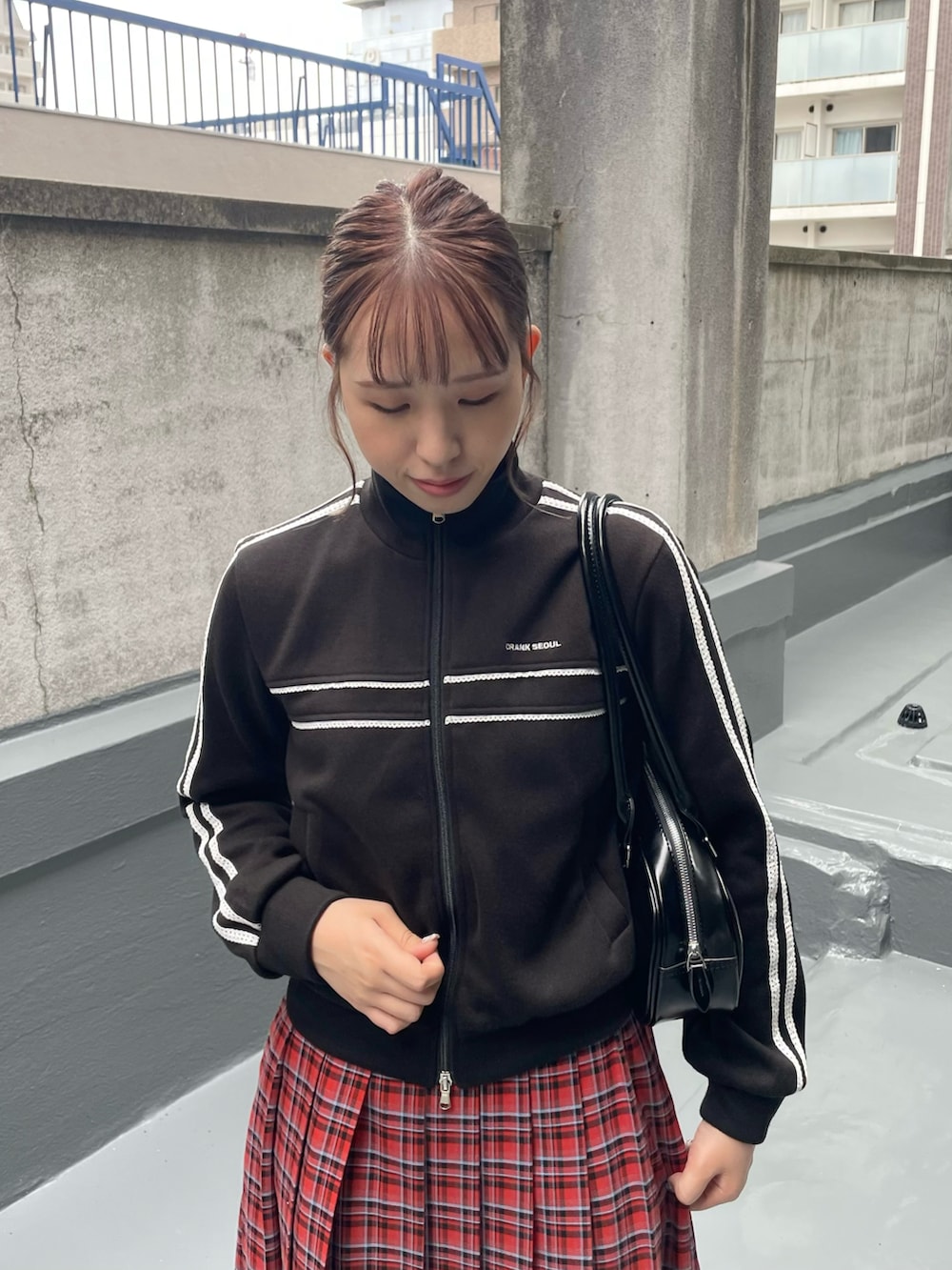 ブラック系のスニーカー、レッド系のスカート、ブラック系のショルダーバッグを着用したレディースの秋コーディネートの4枚目の写真