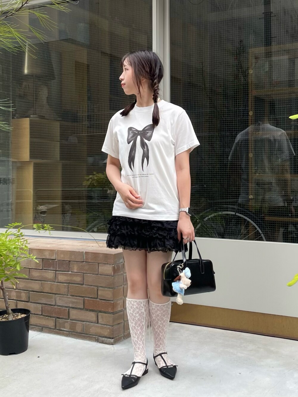 ホワイト系のTシャツ/カットソー、ブラック系のパンプス、ブラック系のハンドバッグを着用したレディースの夏コーディネートの3枚目の写真